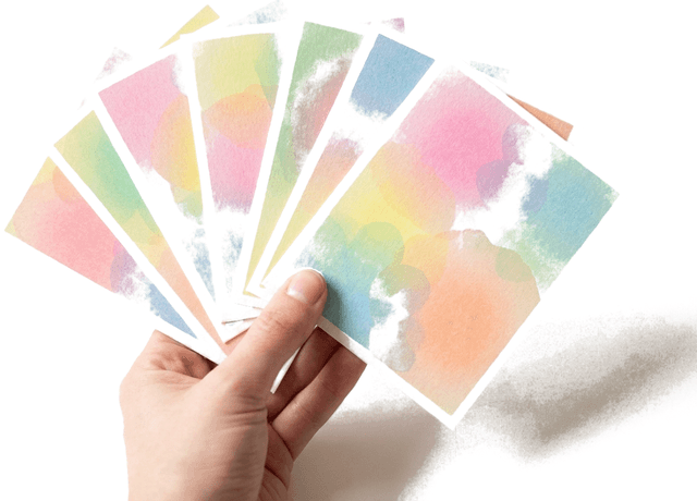 A hand holding a fanned deck of pastel gradient printed cards